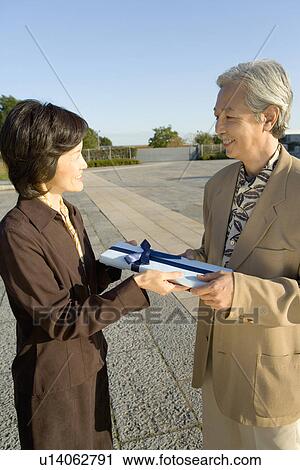 Stock Image - A Mature Couple Giving a Present, Three Quarter Length. Fotosearch