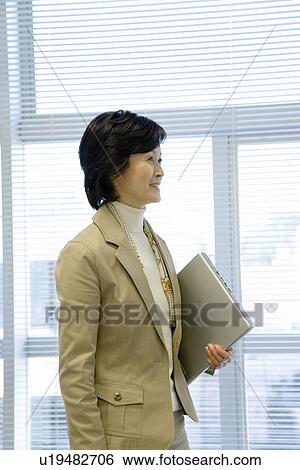 A Mature Woman Holding a Laptop Computer, Side View, Waist Up View Large Photo Image Stock Photograph - A Mature Woman Holding a Laptop Computer, Side View, Waist Up. Fotosearch