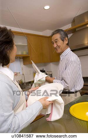 Stock Photo - A Senior Adult Couple Cleaning Dishes Together, Side View. Fotosearch