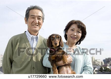 Stock Image - A Senior Adult Couple with a Dog, Front View. Fotosearch