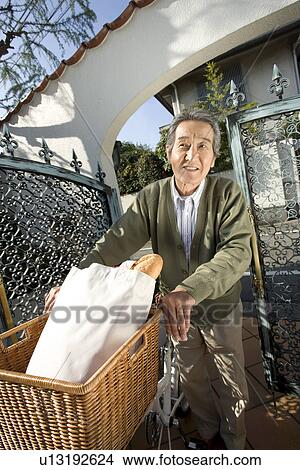 Picture - A Senior Adult Man on a Bicycle with Some Bread in its Basket, High Angle View. Fotosearch