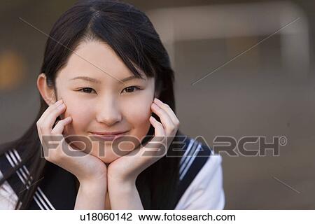 Portrait of a teenage girl sitting and resting chin in hands in schoolyard, smiling and looking at camera View Large Photo Image Stock Image - Portrait of a teenage girl sitting and resting chin in hands in schoolyard, smiling and looking at camera. Fotosearch