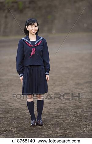 Stock Photo - Portrait of a teenage girl standing in schoolyard, smiling and looking at camera. Fotosearch