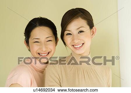 Picture - Portrait of two women smiling, looking at camera, front view. Fotosearch