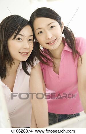 Picture - Portrait of Two Young Twin Sisters, Smiling, Front View. Fotosearch