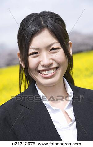 Stock Photograph - Smiling Businesswoman In Rape Blossoms, Portrait, Front View, Differential Focus. Fotosearch
