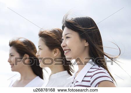 Stock Photo - Three young women, smiling, side view. Fotosearch