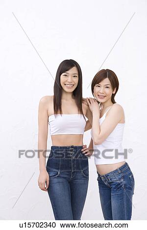 Stock Image - Two young women, smiling, front view. Fotosearch