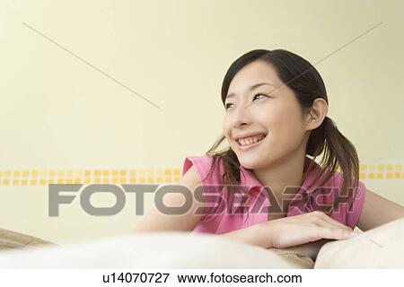 Young Woman Lying on Sofa, Smiling, Front View View Large Photo Image Stock Photo - Young Woman Lying on Sofa, Smiling, Front View. Fotosearch