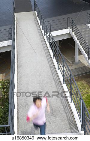 Stock Photo - Man running on footbridge, high angle view, blurred motion, Japan. Fotosearch