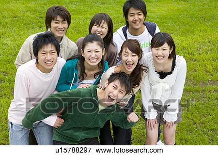 Stock Photo - Portrait of medium group of young people on lawn, smiling and looking at camera, high angle view, Japan. Fotosearch