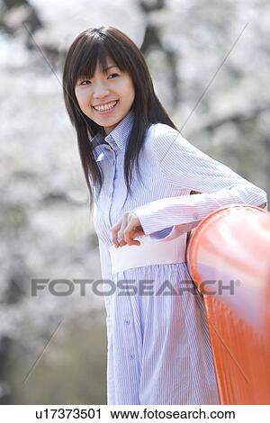 Stock Image - Young Woman Leaning on a Rail, Side View, Differential Focus. Fotosearch