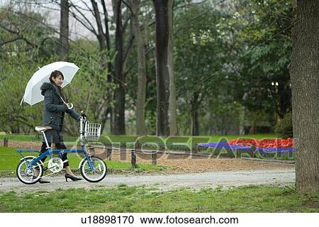 Young Woman Pushing the Bicycle in the Park, Side View View Large Photo Image Stock Image - Young Woman Pushing the Bicycle in the Park, Side View . Fotosearch