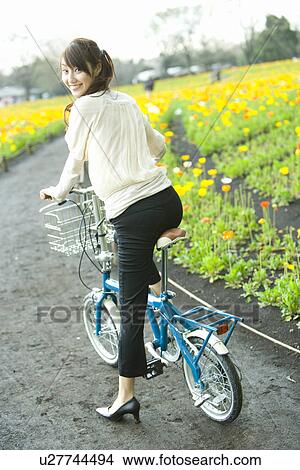 Picture - Young Woman Riding on a Bicycle, Rear View, Looking at Camera. Fotosearch