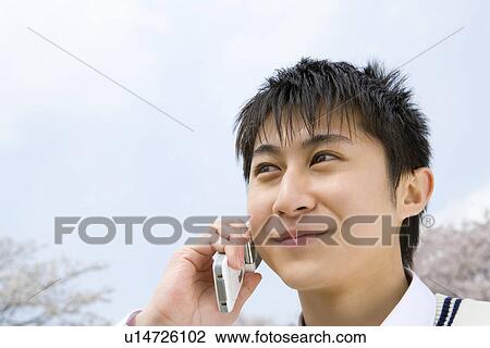 Stock Image - High School Boy Talking on Mobile Phone Under the Sky. Fotosearch