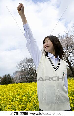 Stock Photograph - High School Girl In Rape Seed Blossom Field, Fist In the Air. Fotosearch