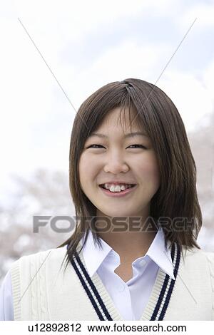 Stock Image - High School Girl Smiling and Cherry Trees in the Background. Fotosearch