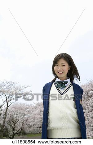 High School Girl Smiling and Looking at Camera, Cherry Blossoms in the Background View Large Photo Image Picture - High School Girl Smiling and Looking at Camera, Cherry Blossoms in the Background. Fotosearch