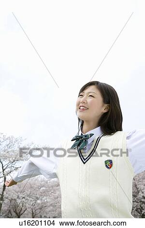High School Girl Spreading Arms, Cherry Blossoms in the Background View Large Photo Image Picture - High School Girl Spreading Arms, Cherry Blossoms in the Background. Fotosearch