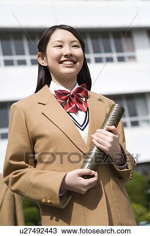 Stock Image - Portrait of a teenage girl holding diploma, smiling. Fotosearch