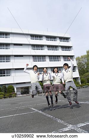 Stock Image - Portrait of four high school students jumping in campus, looking at camera, side by side. Fotosearch