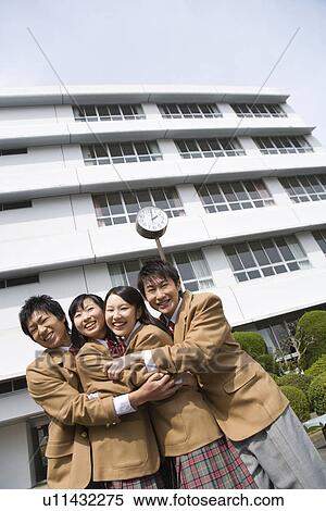 Stock Photography - Portrait of four high school students embracing each other, smiling and looking at camera. Fotosearch