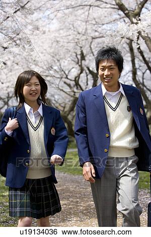 Stock Photograph - Two High School Students on Path with Cherry Blossoms in the Background. Fotosearch
