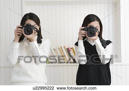 Portrait of twin sisters holding cameras and photographing, front view View Large Photo Image Stock Image - Portrait of twin sisters holding cameras and photographing, front view. Fotosearch