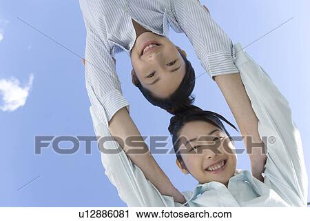 Portrait of twin sisters under the blue sky, smiling and looking at camera, low angle view View Large Photo Image Stock Image - Portrait of twin sisters under the blue sky, smiling and looking at camera, low angle view. Fotosearch