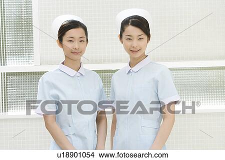 Portrait of two nurses, twin sisters, smiling and looking at camera, front view View Large Photo Image Picture - Portrait of two nurses, twin sisters, smiling and looking at camera, front view. Fotosearch