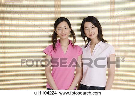 Portrait of Two Young Twin Sisters, Smiling, Front View View Large Photo Image Picture - Portrait of Two Young Twin Sisters, Smiling, Front View. Fotosearch