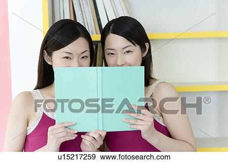 Portrait of Two Young Twin Sisters Reading a Book, Smiling, Front View View Large Photo Image Stock Photo - Portrait of Two Young Twin Sisters Reading a Book, Smiling, Front View. Fotosearch