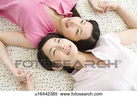 Stock Photography - Portrait of Two Young Twin Sisters Lying on Back, Smiling, High Angle View. Fotosearch