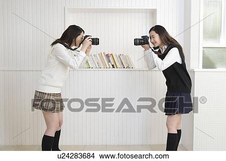 Twin sisters holding cameras and photographing each other, side view View Large Photo Image Picture - Twin sisters holding cameras and photographing each other, side view. Fotosearch