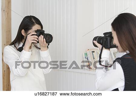 Twin sisters holding cameras and photographing each other, front view, side view View Large Photo Image Stock Photo - Twin sisters holding cameras and photographing each other, front view, side view. Fotosearch