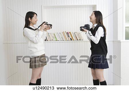 Twin sisters smiling and holding cameras, side view View Large Photo Image Stock Image - Twin sisters smiling and holding cameras, side view. Fotosearch
