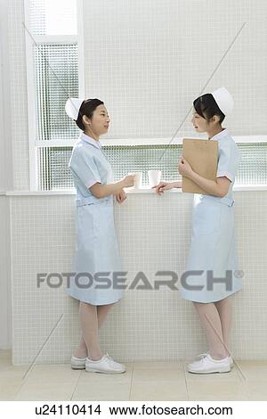 Picture - Two nurses talking in hospital, twin sisters, side view. Fotosearch
