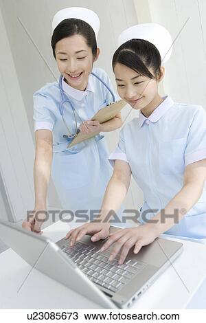 Two nurses using laptop, twin sisters, front view View Large Photo Image Stock Image - Two nurses using laptop, twin sisters, front view. Fotosearch