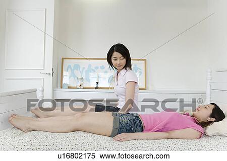 Woman looking down her sister lying on bed, twin sisters, side view View Large Photo Image Stock Photography - Woman looking down her sister lying on bed, twin sisters, side view. Fotosearch