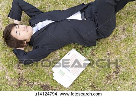 Picture - Businessman Lying on Grass, High angle View. Fotosearch