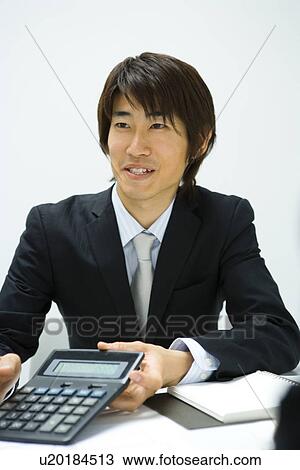 Stock Image - Businessman Showing a Calculator, Front View. Fotosearch