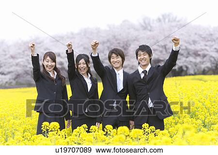 Stock Photo - Businessmen and Businessmen Holding Arms Up in Rape Field, Laughing, Three Quarter Length. Fotosearch