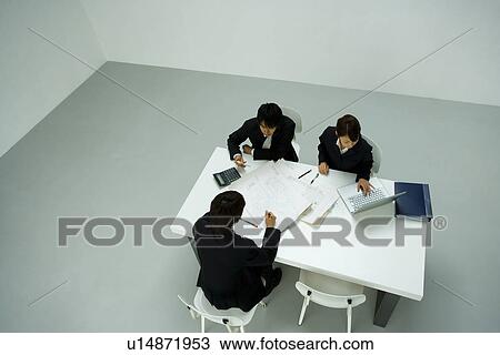 Stock Image - Businessmen and Businesswoman In Meeting, High Angle View. Fotosearch