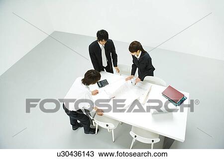 Stock Image - Businessmen and Businesswoman In Meeting, High Angle View. Fotosearch