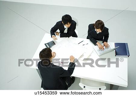 Stock Photo - Businessmen and Businesswoman In Meeting, High Angle View. Fotosearch