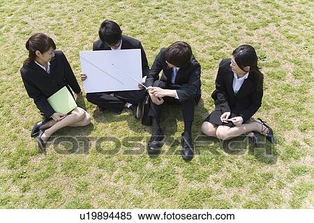 Stock Photography - Businessmen and Businesswomen Sitting On Grass, High Angle View, Full Length. Fotosearch