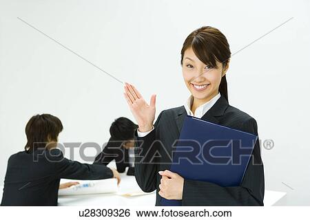 Stock Photograph - Portrait of a Businesswoman and Businessmen talking in the Background, Front View. Fotosearch