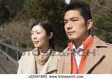 Stock Image - Japanese couple looking away on the bridge, front view, Japan. Fotosearch