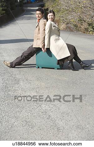 Japanese couple on the road, sitting on a suitcase, side view, copy space, Japan View Large Photo Image Stock Photograph - Japanese couple on the road, sitting on a suitcase, side view, copy space, Japan. Fotosearch