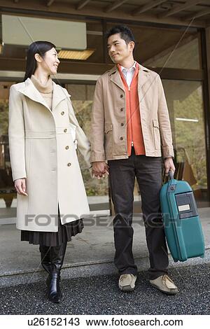 Stock Image - Japanese couple smiling to each other in front of the Japanese inn, front view, Japan. Fotosearch